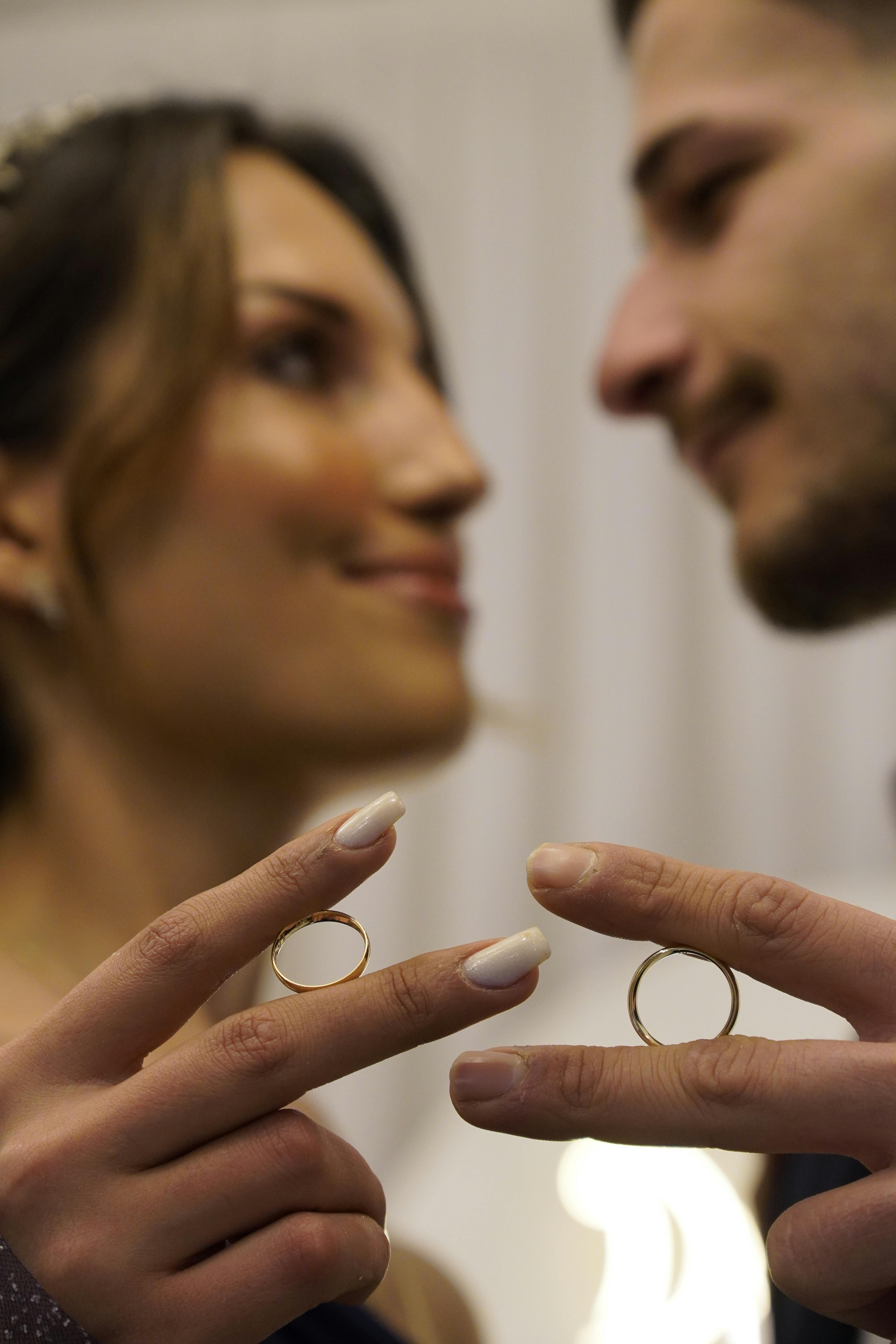 Close-up of a couple's hands exhibiting wedding rings, capturing a moment of love and commitment.