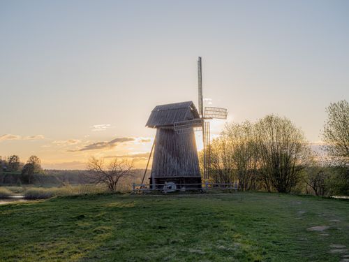 Free Charming rustic windmill at sunset, set in a tranquil rural landscape, evokes a peaceful countryside atmosphere. Stock Photo