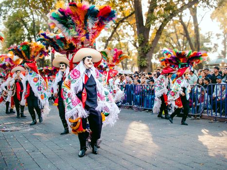 Colorful festival parade featuring traditional costumes and feathered hats, attracting a lively crowd.