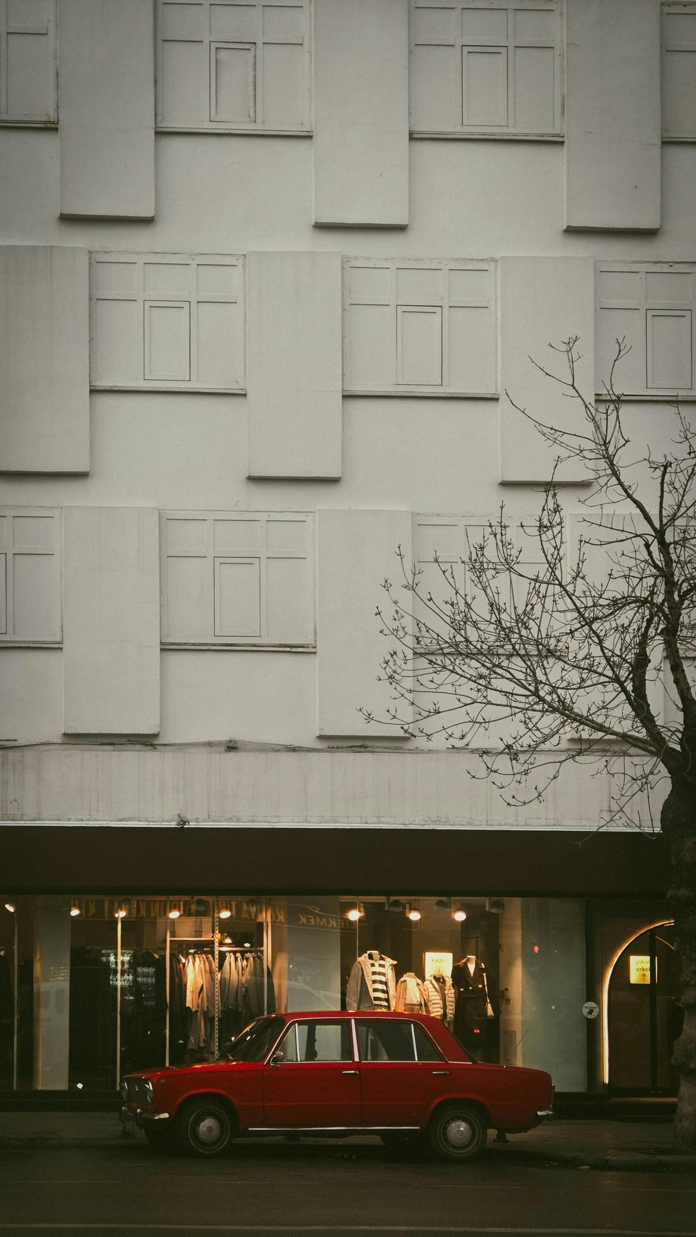 Gratis Un coche rojo antiguo aparcado delante de un edificio moderno en Konya, Turquía, durante el día. Foto de stock