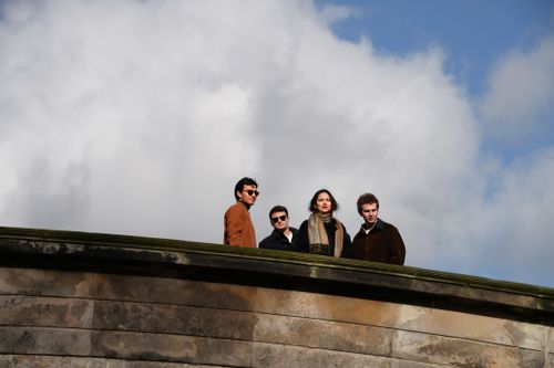 Free Four adults standing on a bridge with a cloudy sky backdrop. Stock Photo