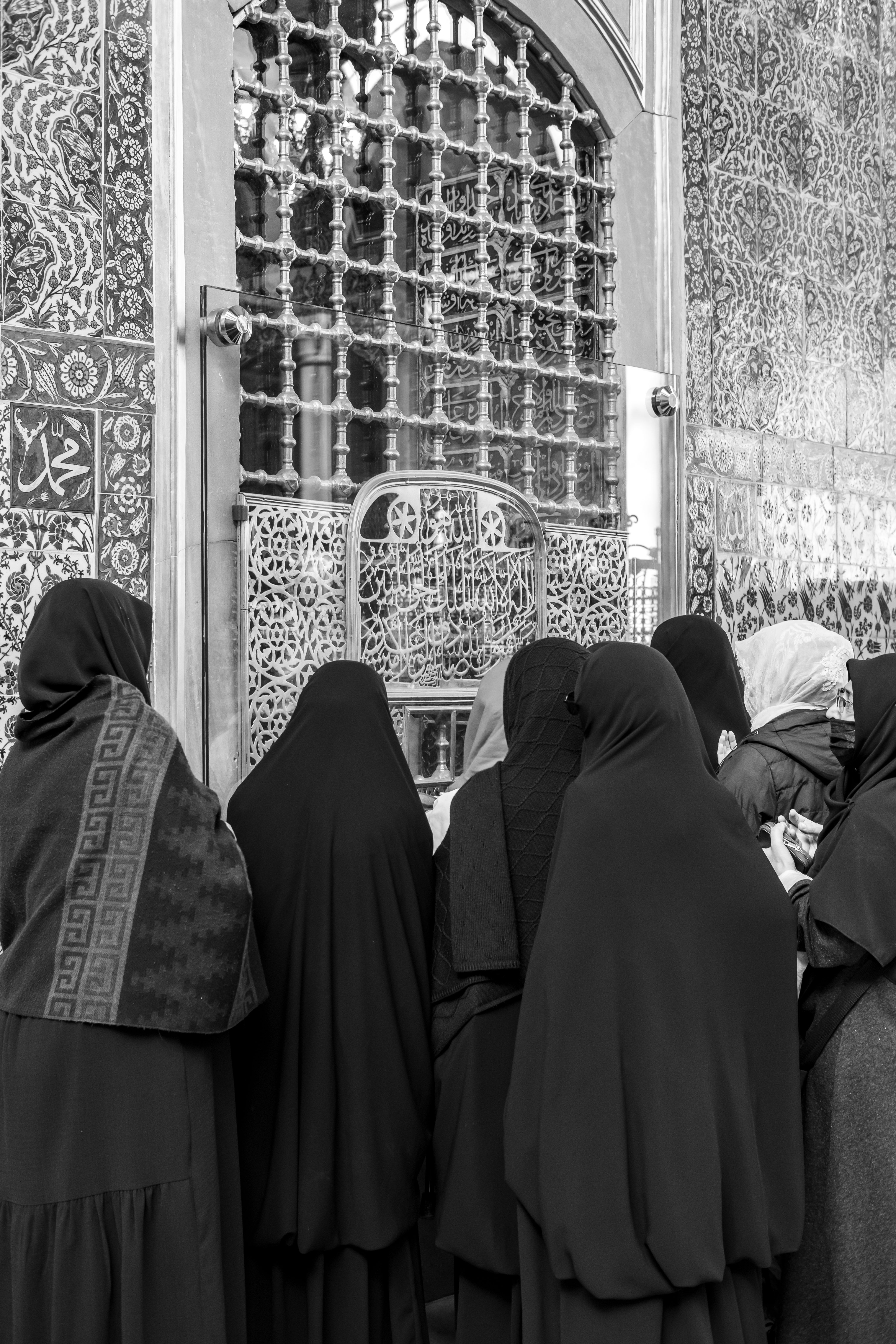 Black and white image of women at Eyüpsultan Mosque in Istanbul, Türkiye, showcasing intricate patterns.