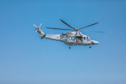 Military helicopter flying over clear blue skies in Doha, Qatar.