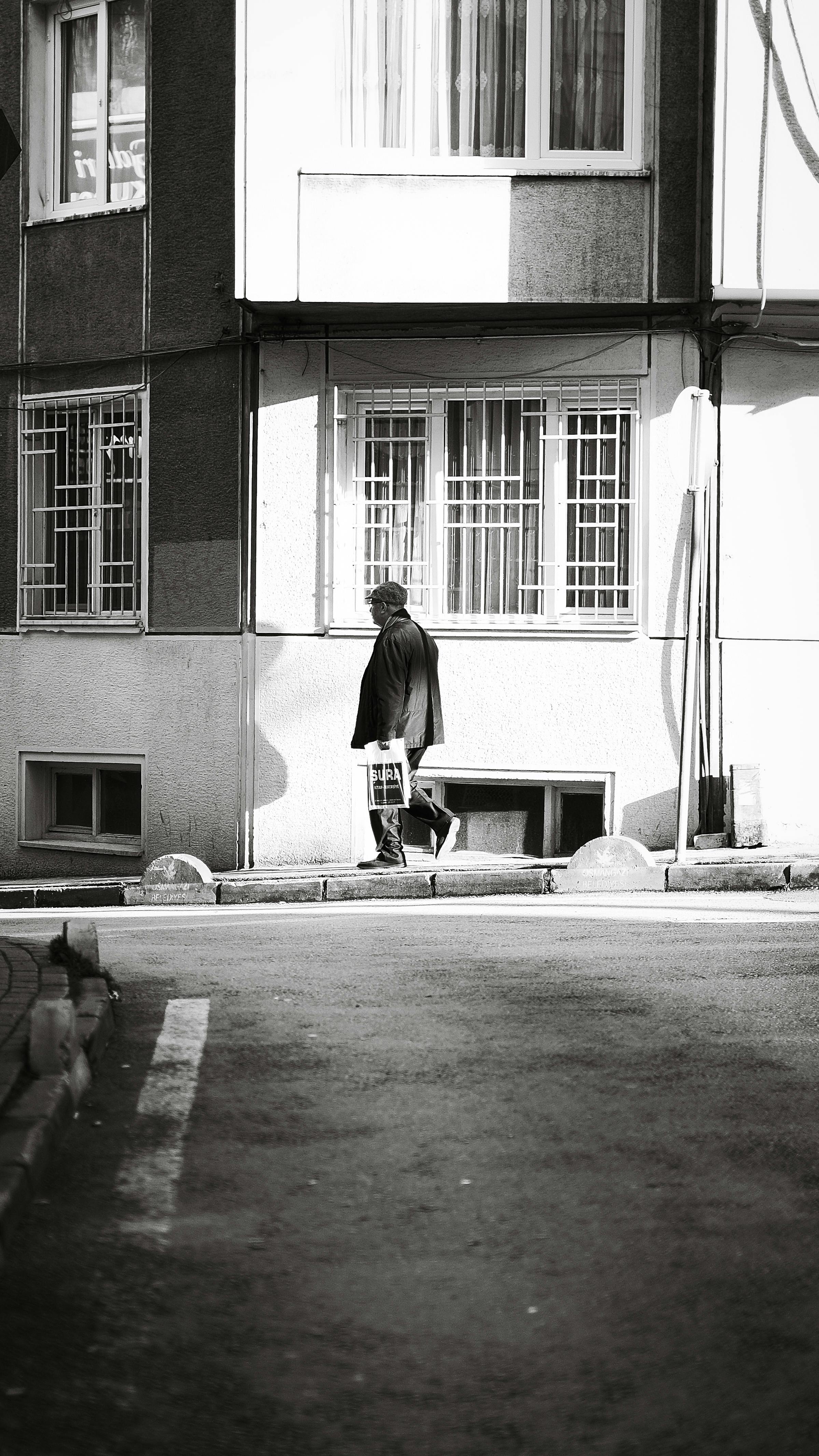 Gratuit Une personne seule transportant une chaise dans un environnement urbain, photographiée en noir et blanc. Photos