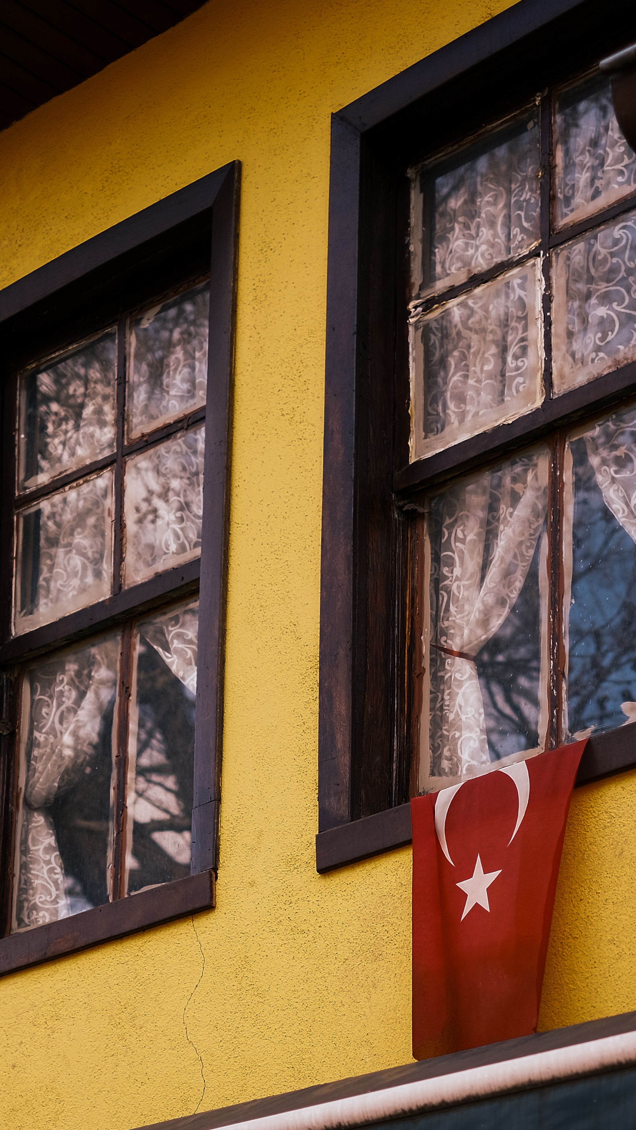 Charming yellow building facade with traditional Turkish flag and vintage window details.