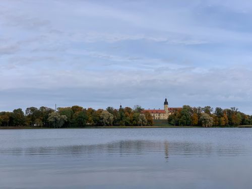 Free A picturesque view of Nesvizh Castle, Belarus, with autumn foliage reflecting on the calm lake waters. Stock Photo