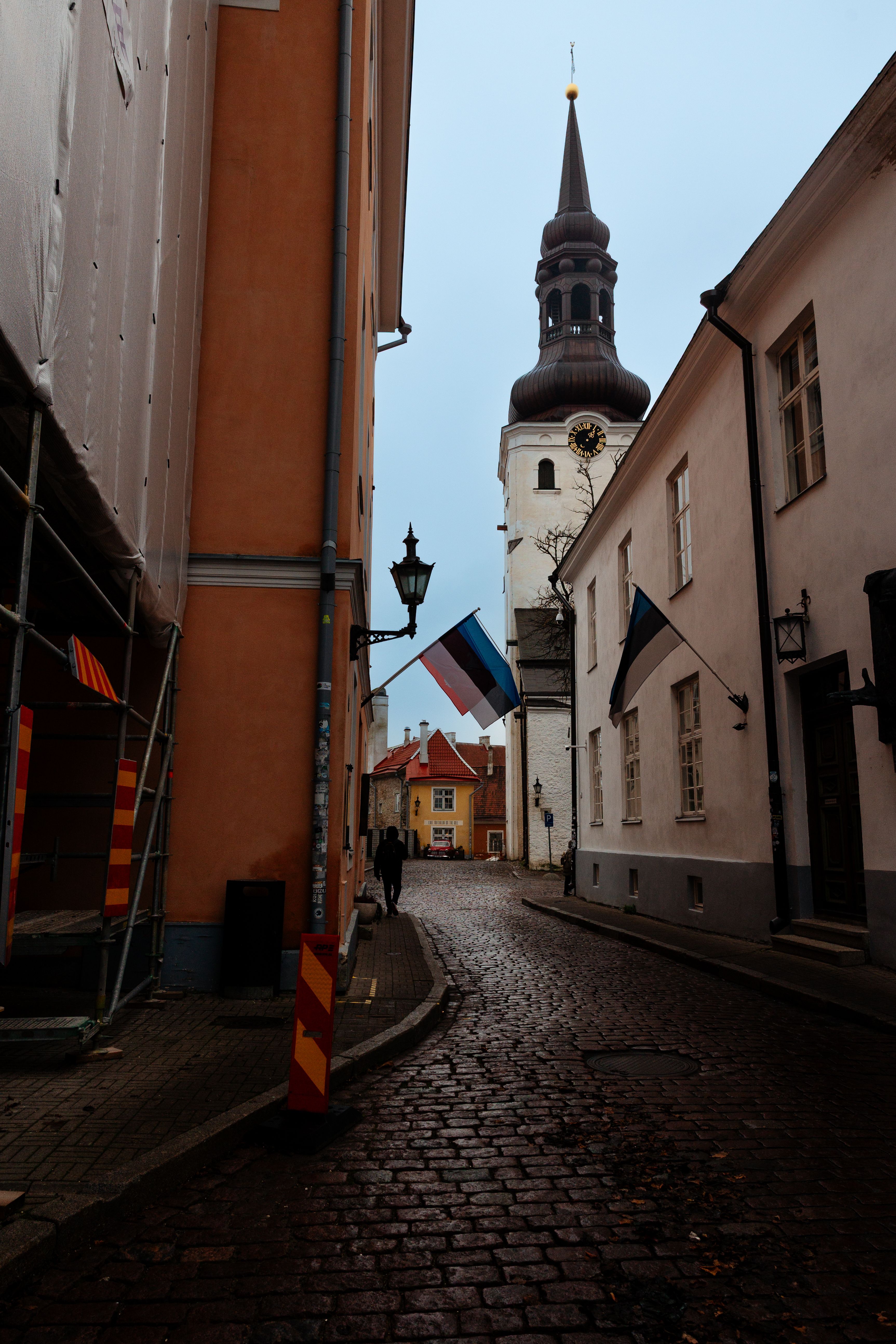 Charming cobblestone street with historical buildings and flags in Tallinn, Estonia.