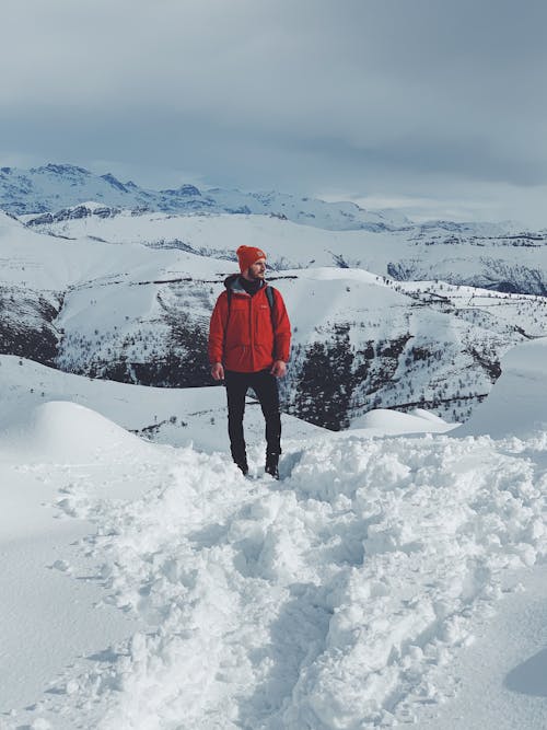 穿紅色夾克的人站立在積雪的地面上