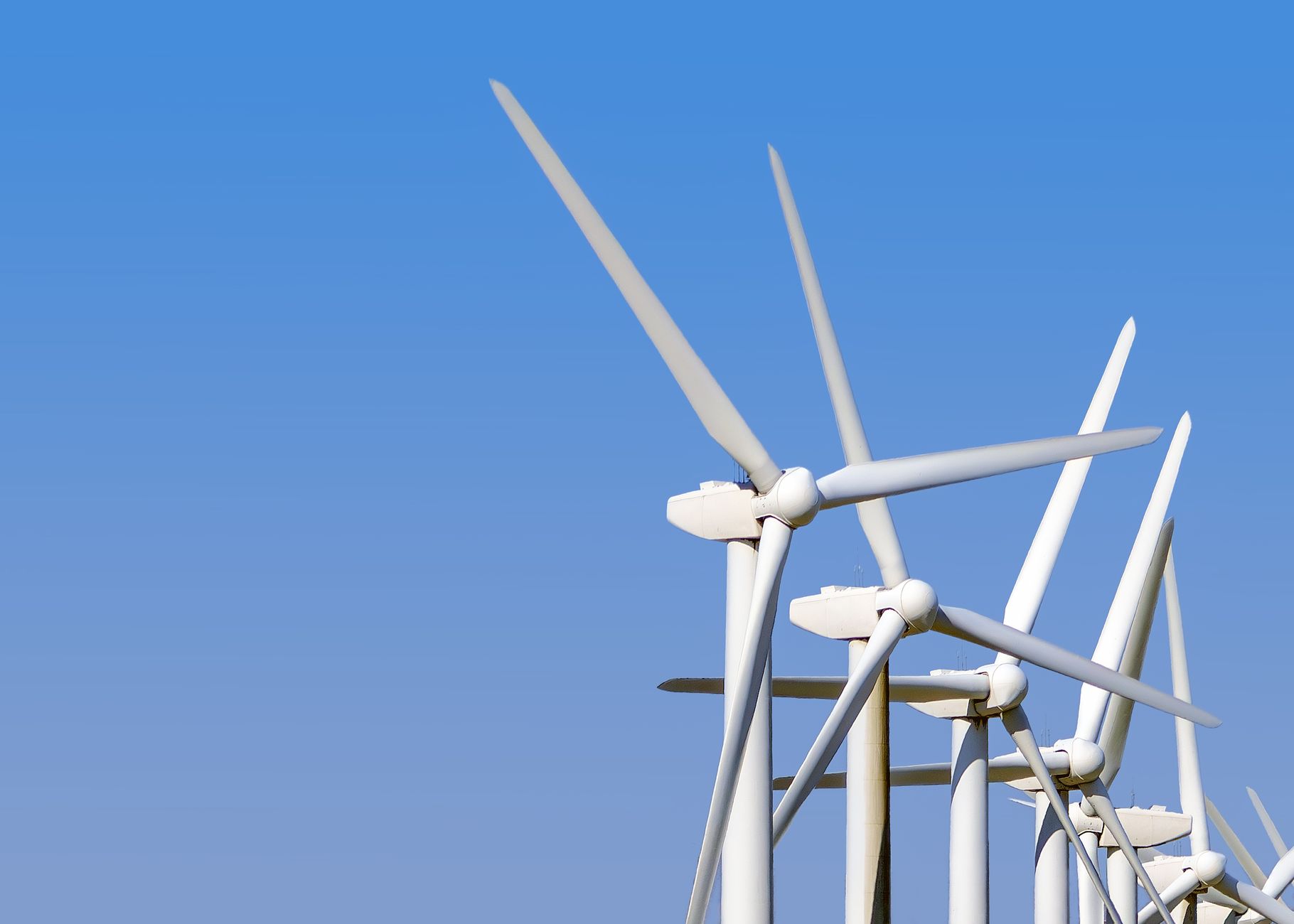 Wind turbines generating clean energy stand tall against a clear blue sky, highlighting sustainable technology.