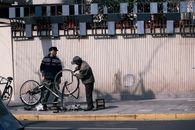 Two men repairing a bicycle on a sunny day in Shanghai.