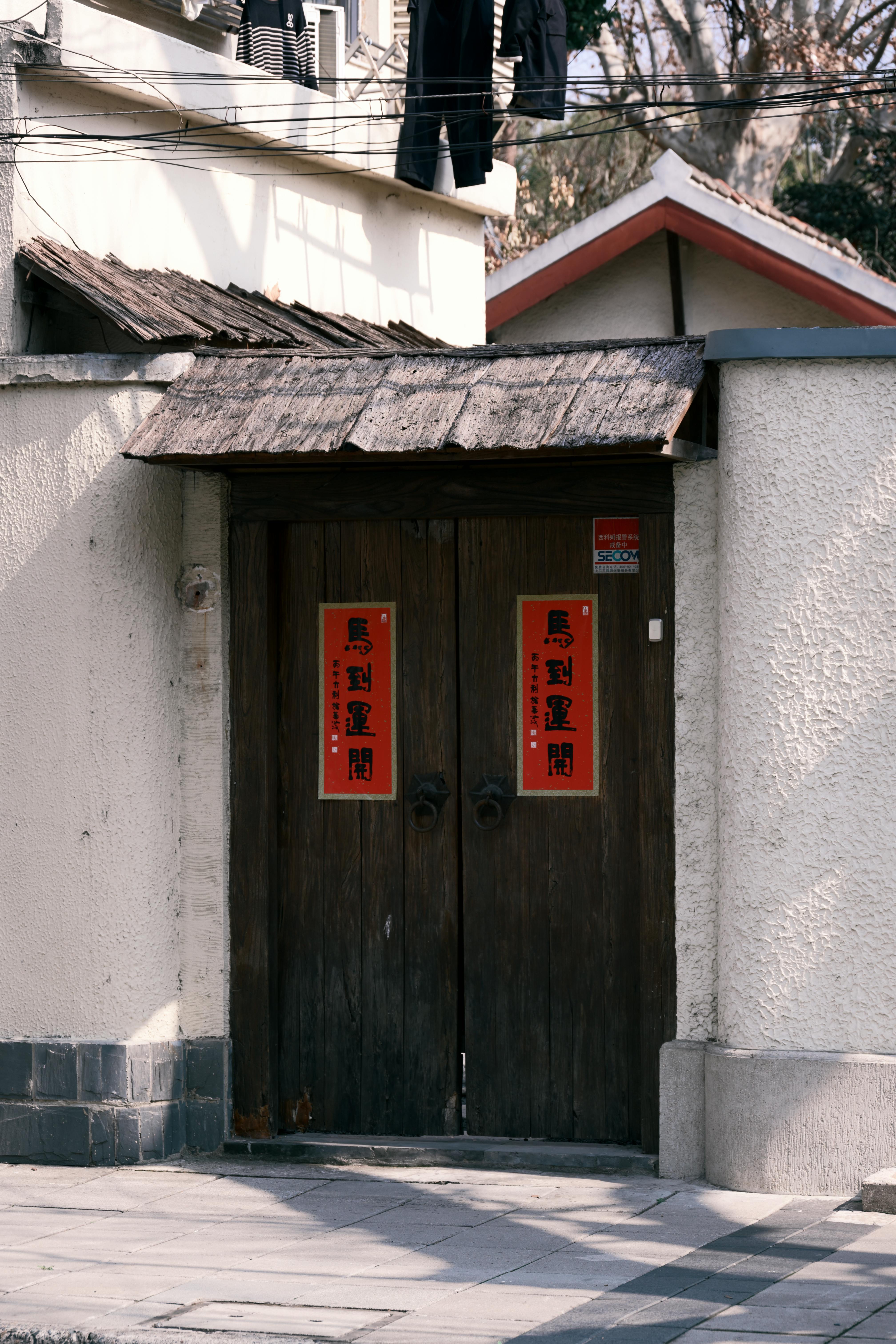 gratis Een traditionele houten deur versierd met rode lantaarns, die de culturele essentie van Shanghai weerspiegelt. Stockfoto
