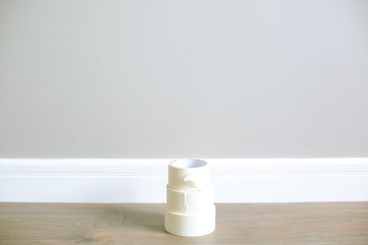 Stack of white masking tape on a wooden floor against a minimal interior wall.