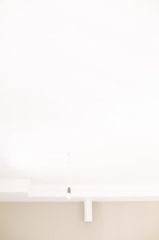 Simple minimalist ceiling design with a hanging light bulb, creating a serene atmosphere.