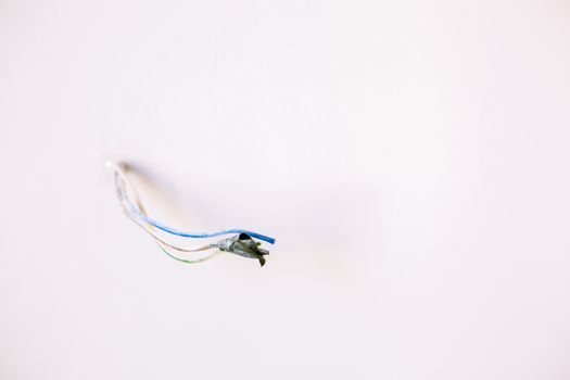 Loose electrical wires protruding from a white wall, ideal for home improvement concepts.