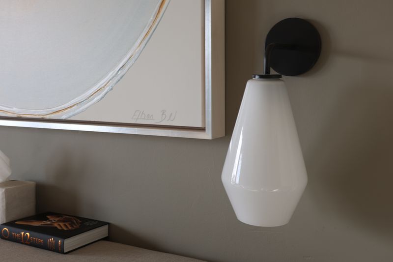 A white glass wall sconce beside a framed canvas, photo by Sole Gomez on Pexels