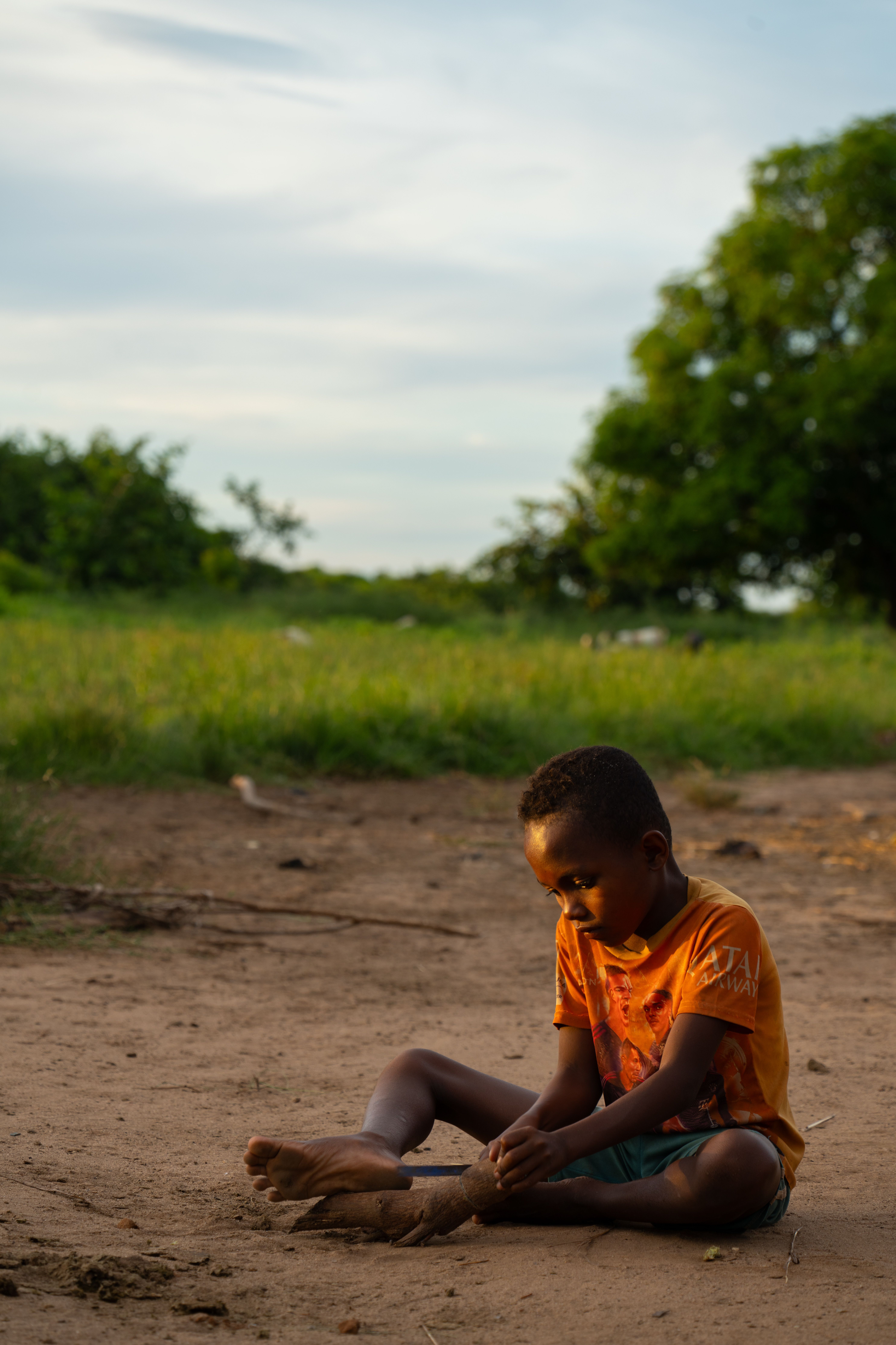 A young boy enjoys playing in a sunlit field in Madagascar, capturing a tranquil, rural scene.