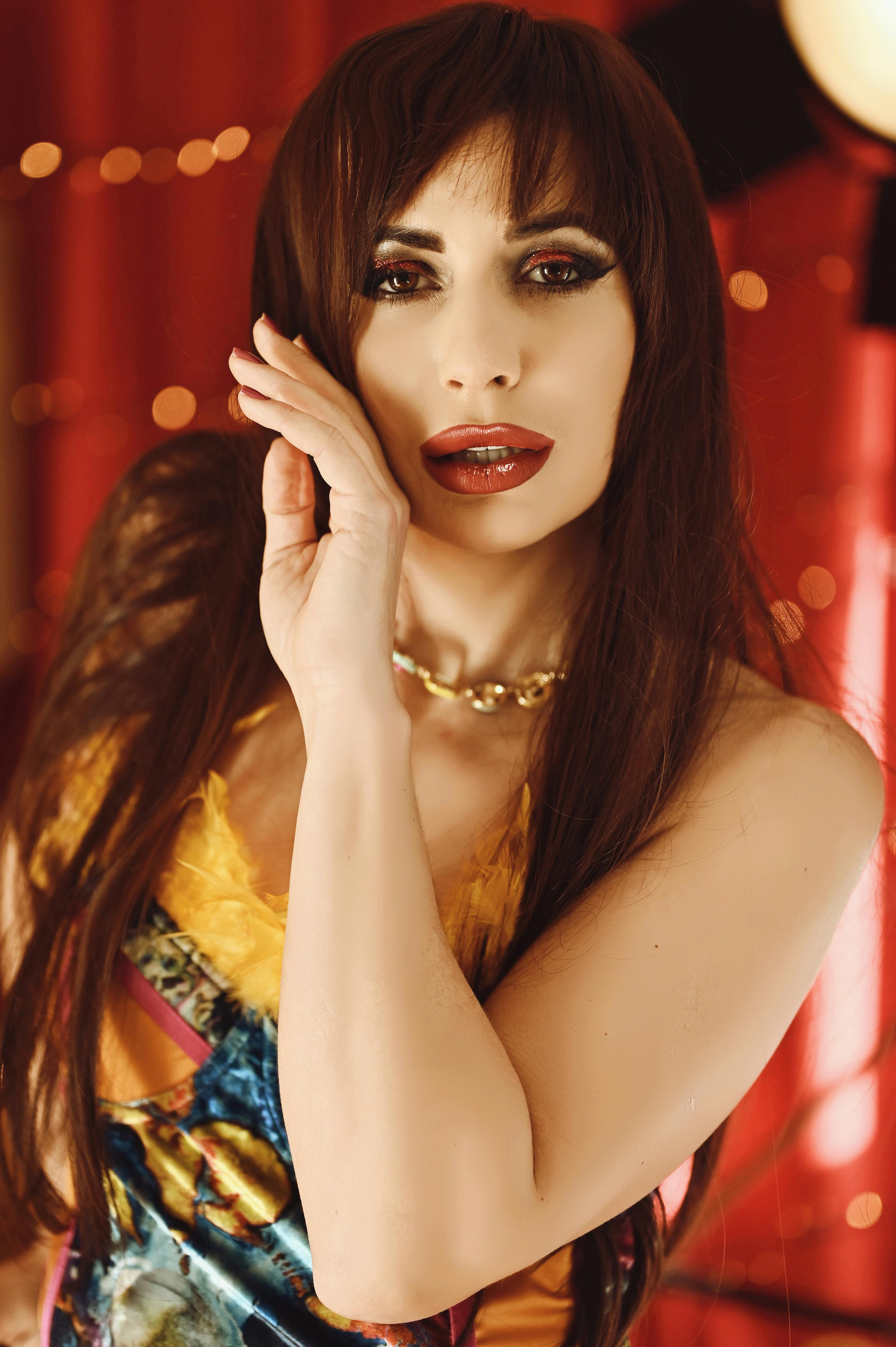 Gratis Donna affascinante in abito elegante che posa con espressione sicura in un ambiente interno. Foto a disposizione