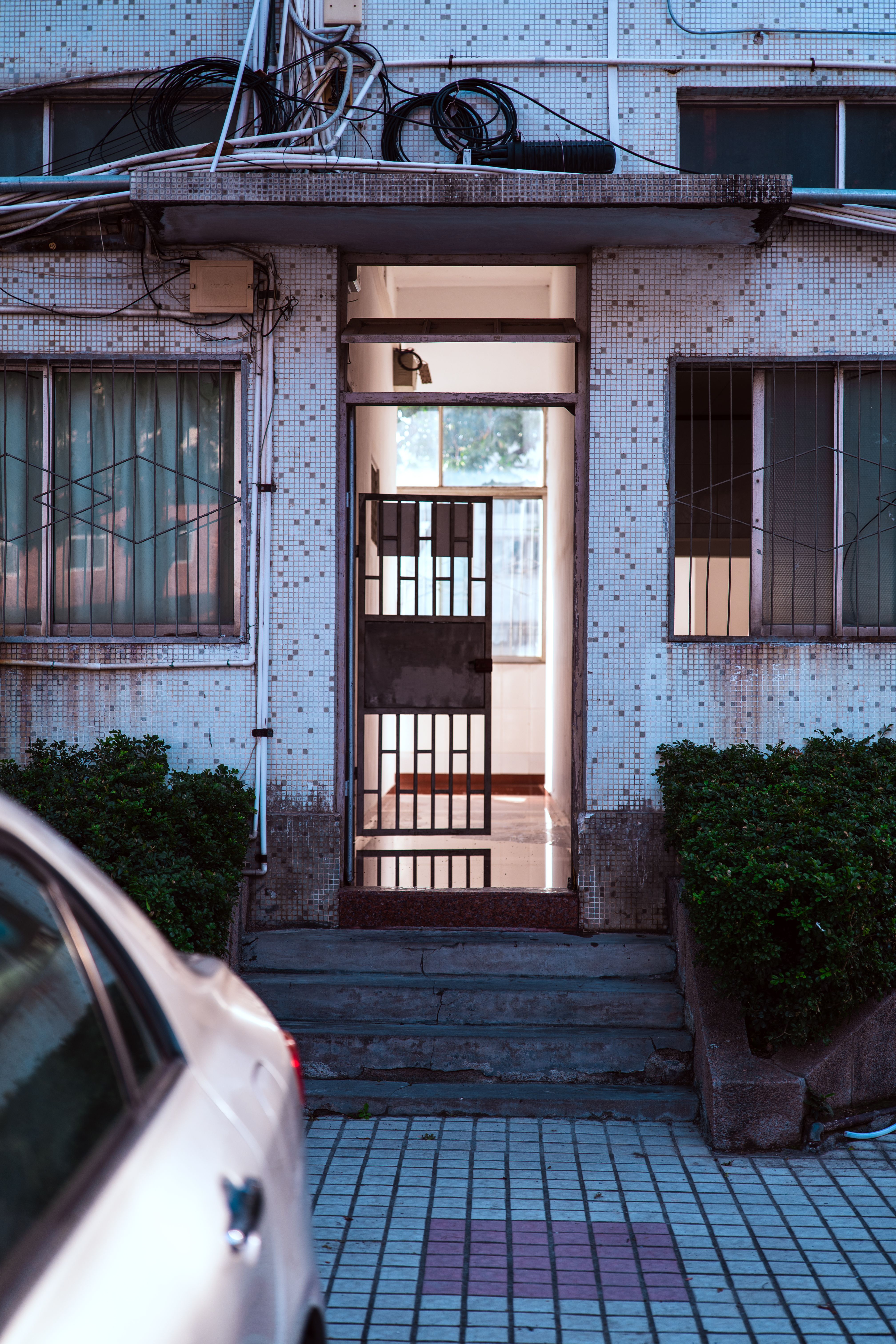 Image of an urban building entrance with open gate at twilight, reflecting modern architecture.