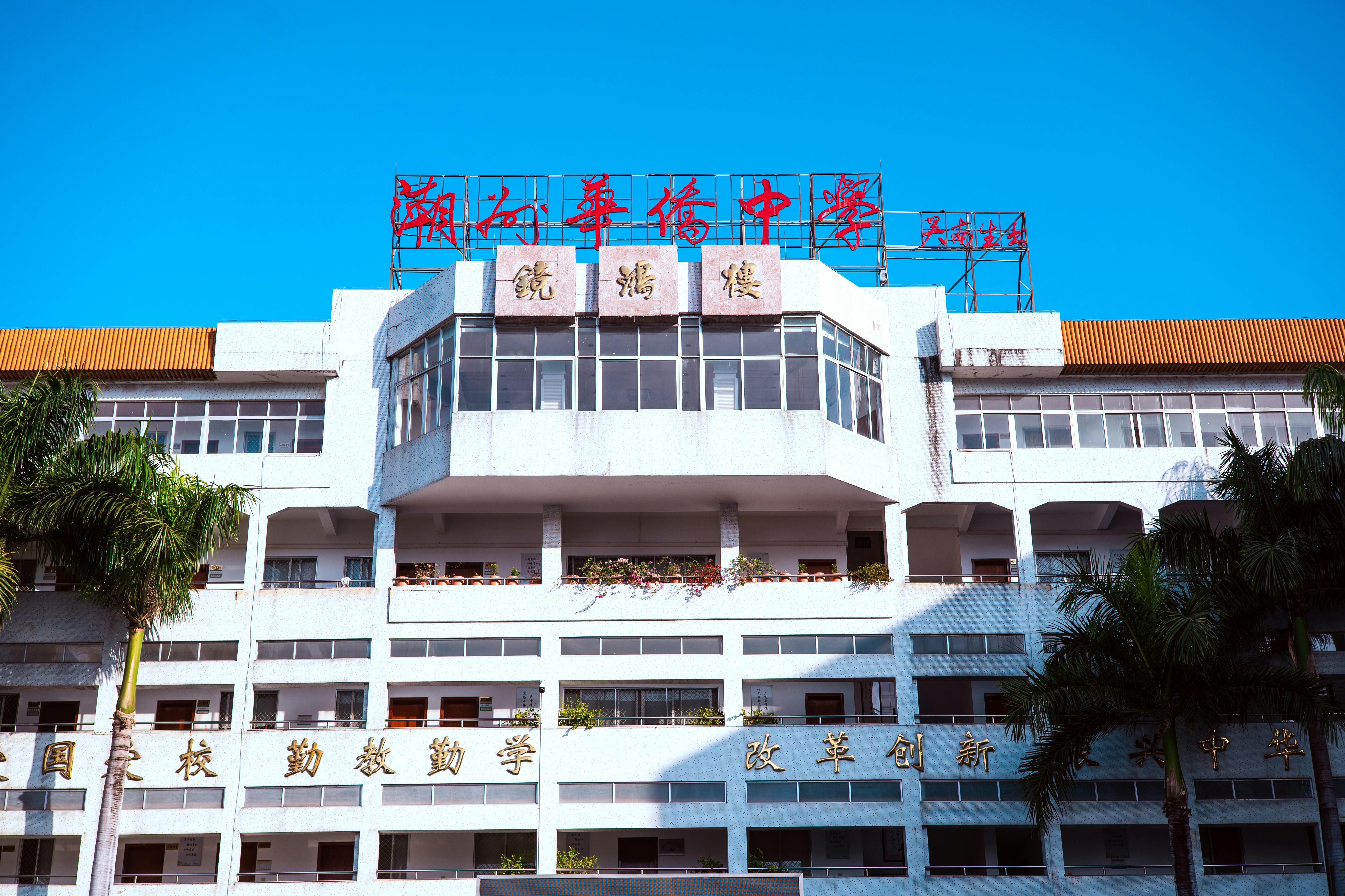A large urban school building with palm trees and bright signage under a clear blue sky.