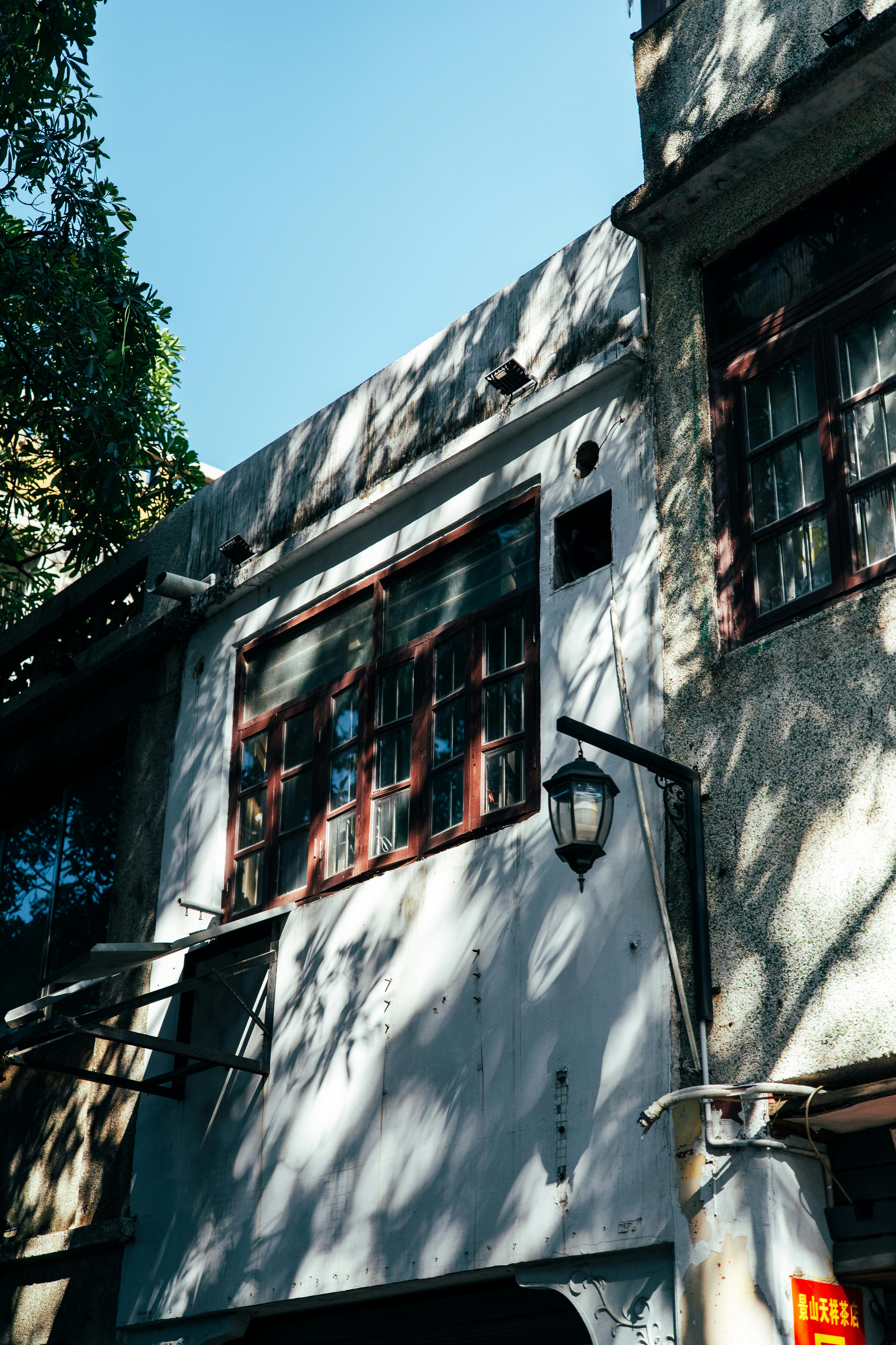 Gratuit Exteriorul unei clădiri urbane însorite, cu ferestre și felinar vintage, surprinzând umbre și texturi. Fotografie de stoc