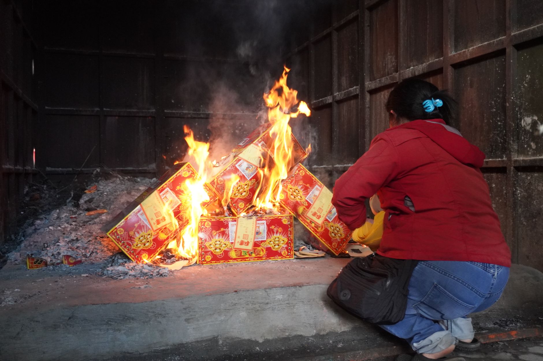 Escena en interiores de una persona realizando un ritual tradicional chino de quema de papel votivo.