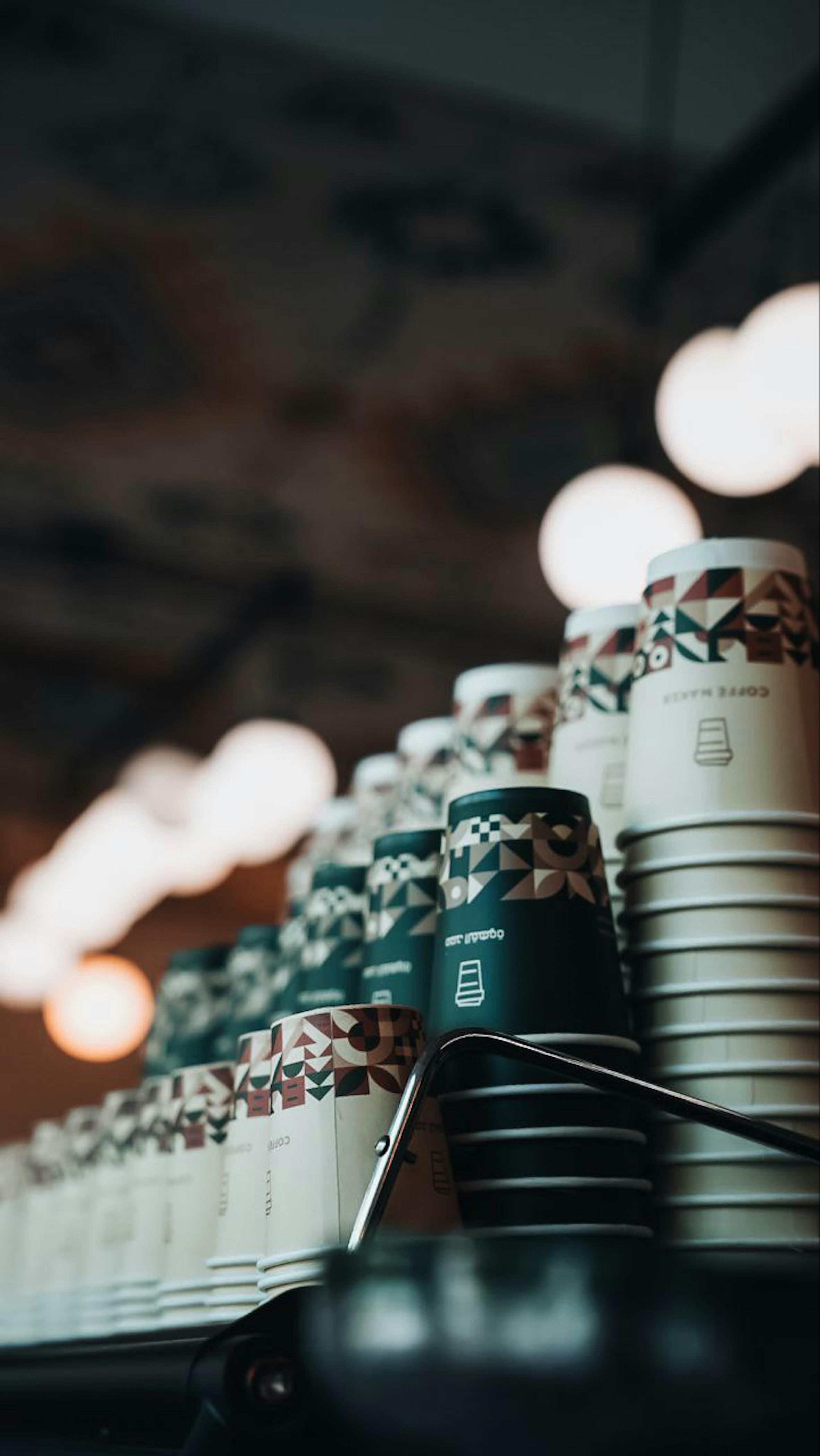 Free Stylish coffee cups stacked in a cozy cafe with a warm ambiance and artistic flair. Stock Photo