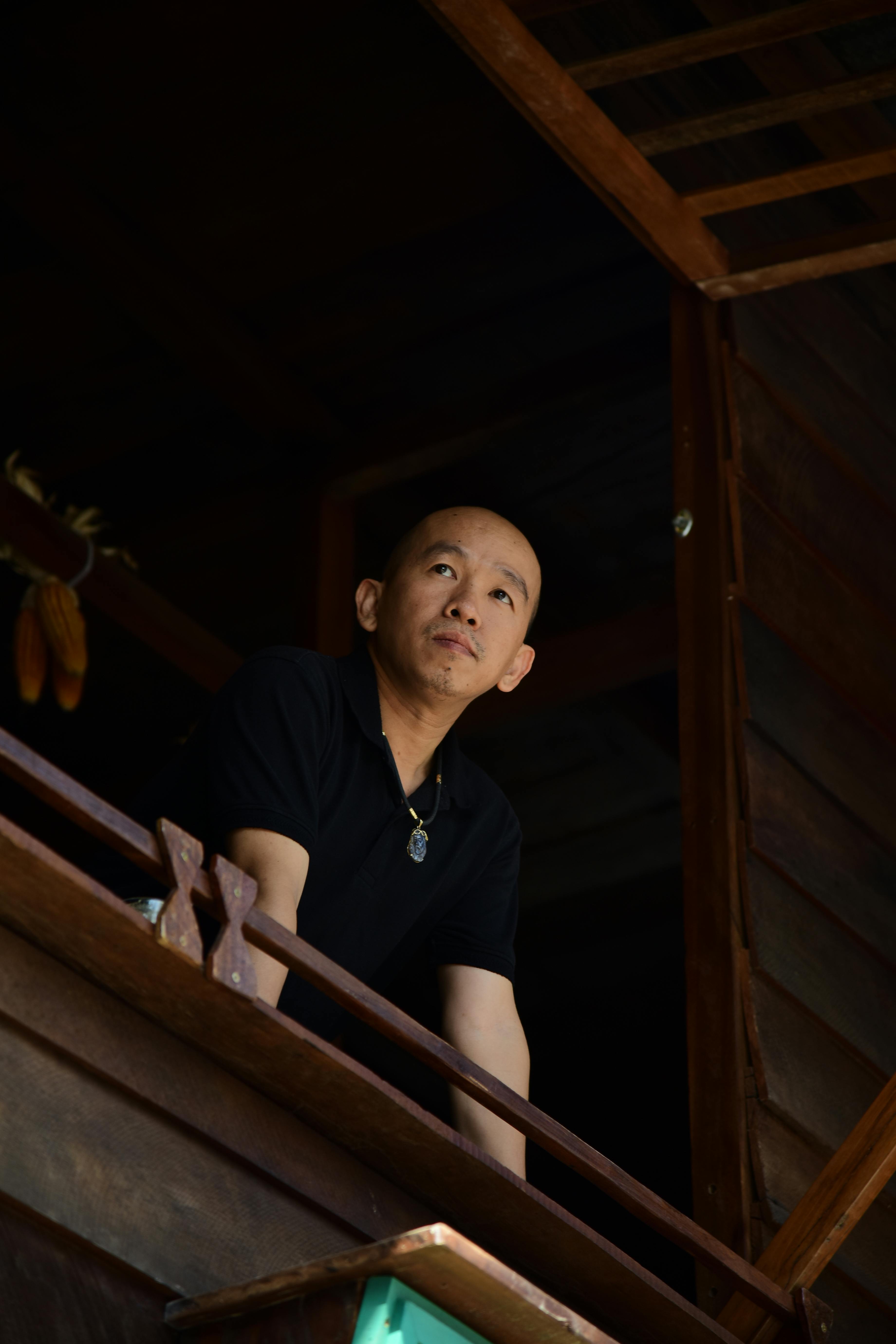 ฟรี ชายคนหนึ่งยืนอยู่บนระเบียงไม้ มองไปยังที่ไกลๆ อย่างครุ่นคิด คลังภาพถ่าย