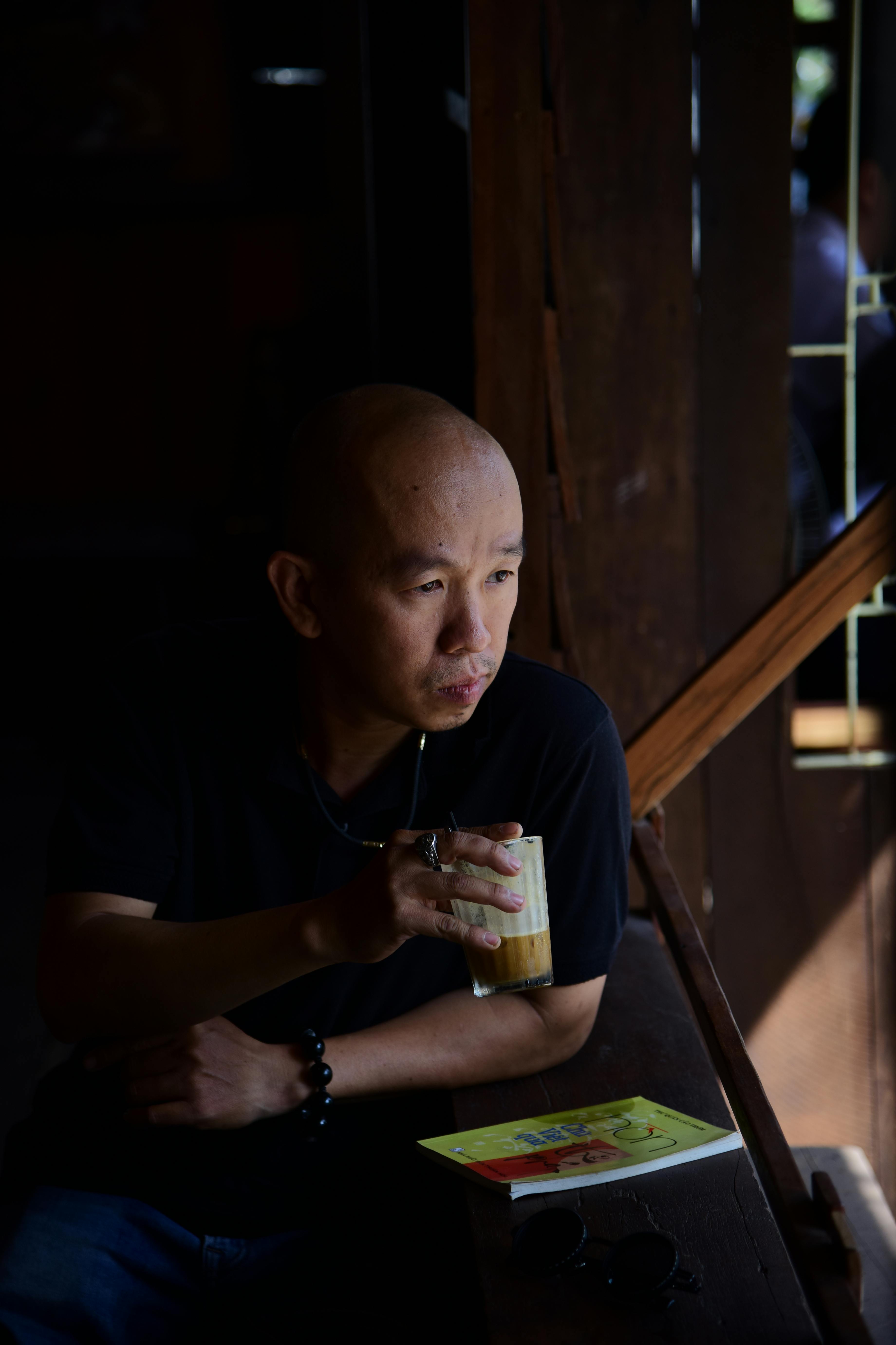 ฟรี ชายผู้ครุ่นคิดคนหนึ่งจิบกาแฟขณะนั่งอยู่ริมหน้าต่างในห้องที่มีแสงสลัว คลังภาพถ่าย