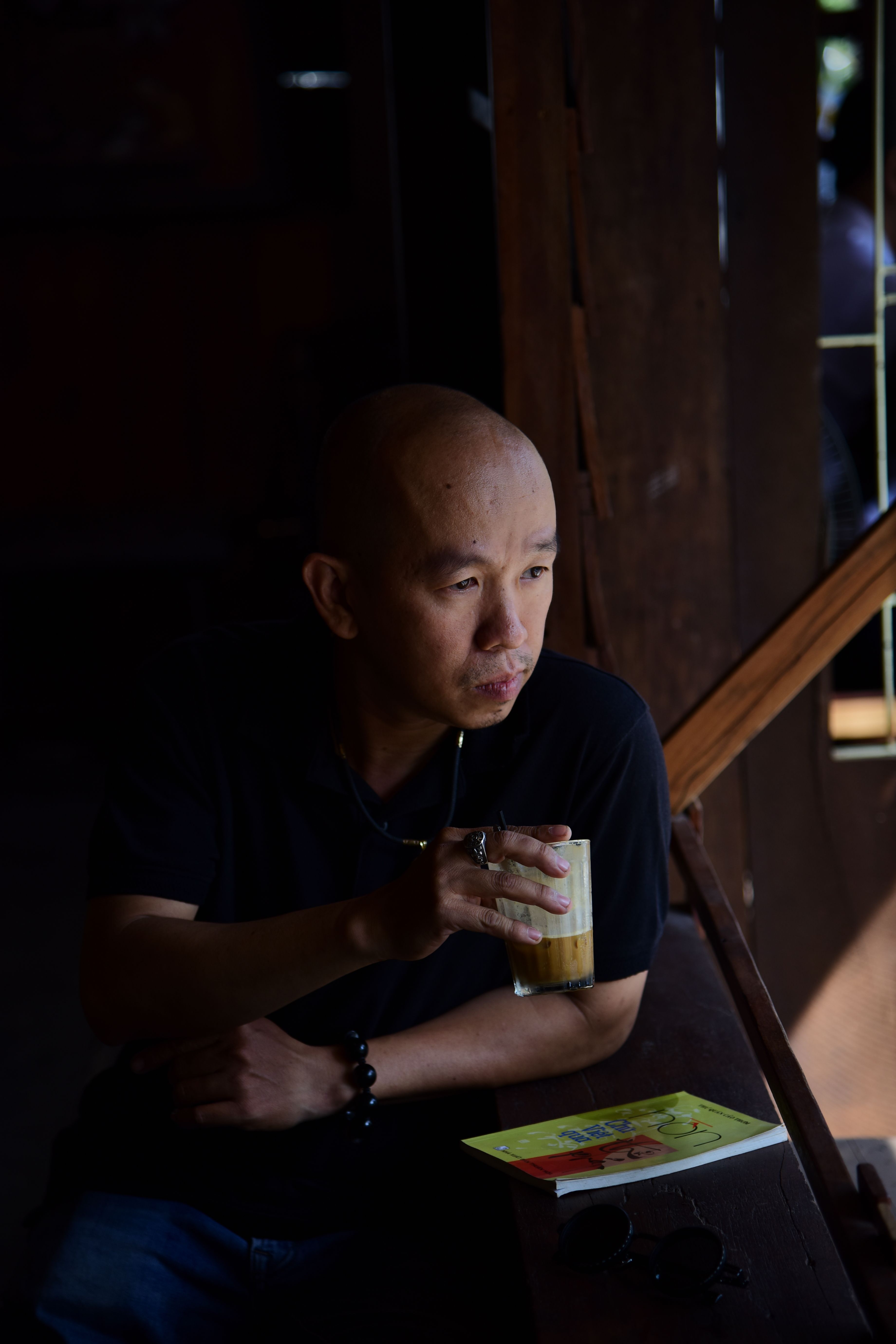 A man enjoys a quiet moment with coffee, book in a dimly lit room.