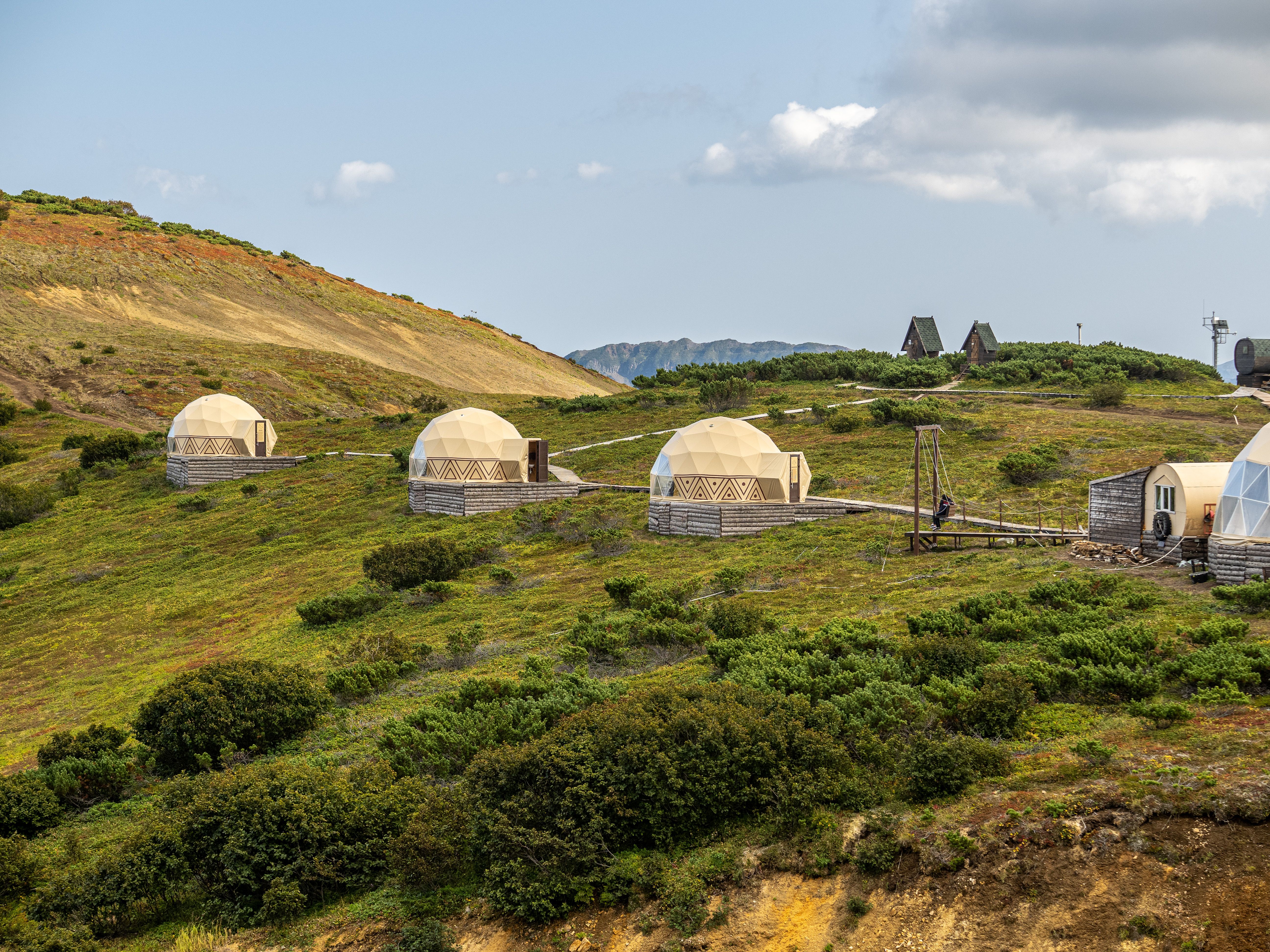 Geodesic domes nestled in the scenic hills of Kamchatka, perfect for eco-friendly travel enthusiasts.