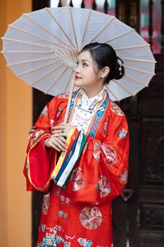 Woman in traditional Asian dress holding a paper umbrella, capturing cultural elegance.