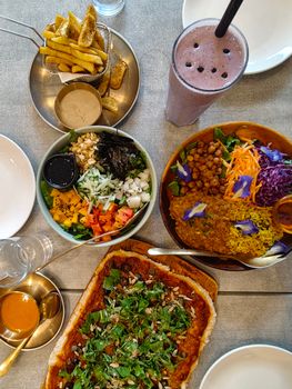 A top-down view of a colorful vegan meal with a variety of fresh dishes and a smoothie.