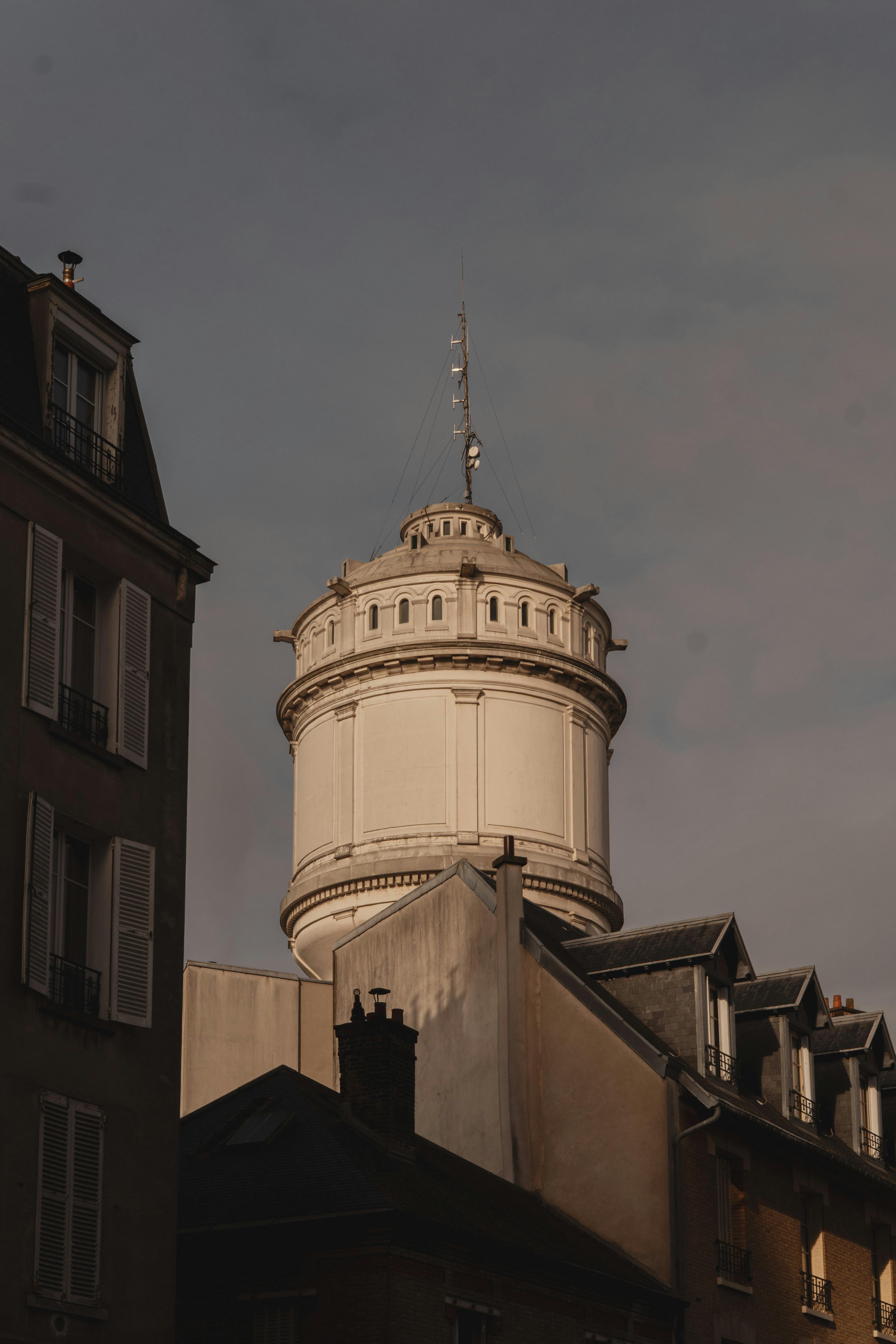 Ücretsiz Gün batımında kasvetli gökyüzü ve Paris çatılarıyla birlikte Montmartre Su Kulesi'nin büyüleyici manzarası. Stok Fotoğraflar