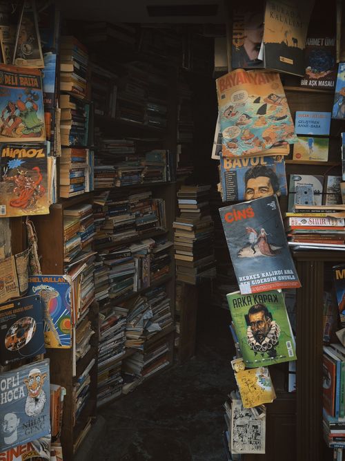 Free Explore a quaint, vintage bookstore filled with stacks of diverse books and comics. Stock Photo
