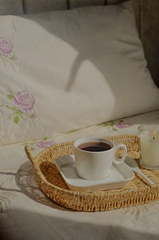 A serene morning scene with a tea cup and candle on a wicker tray, perfect for relaxation.