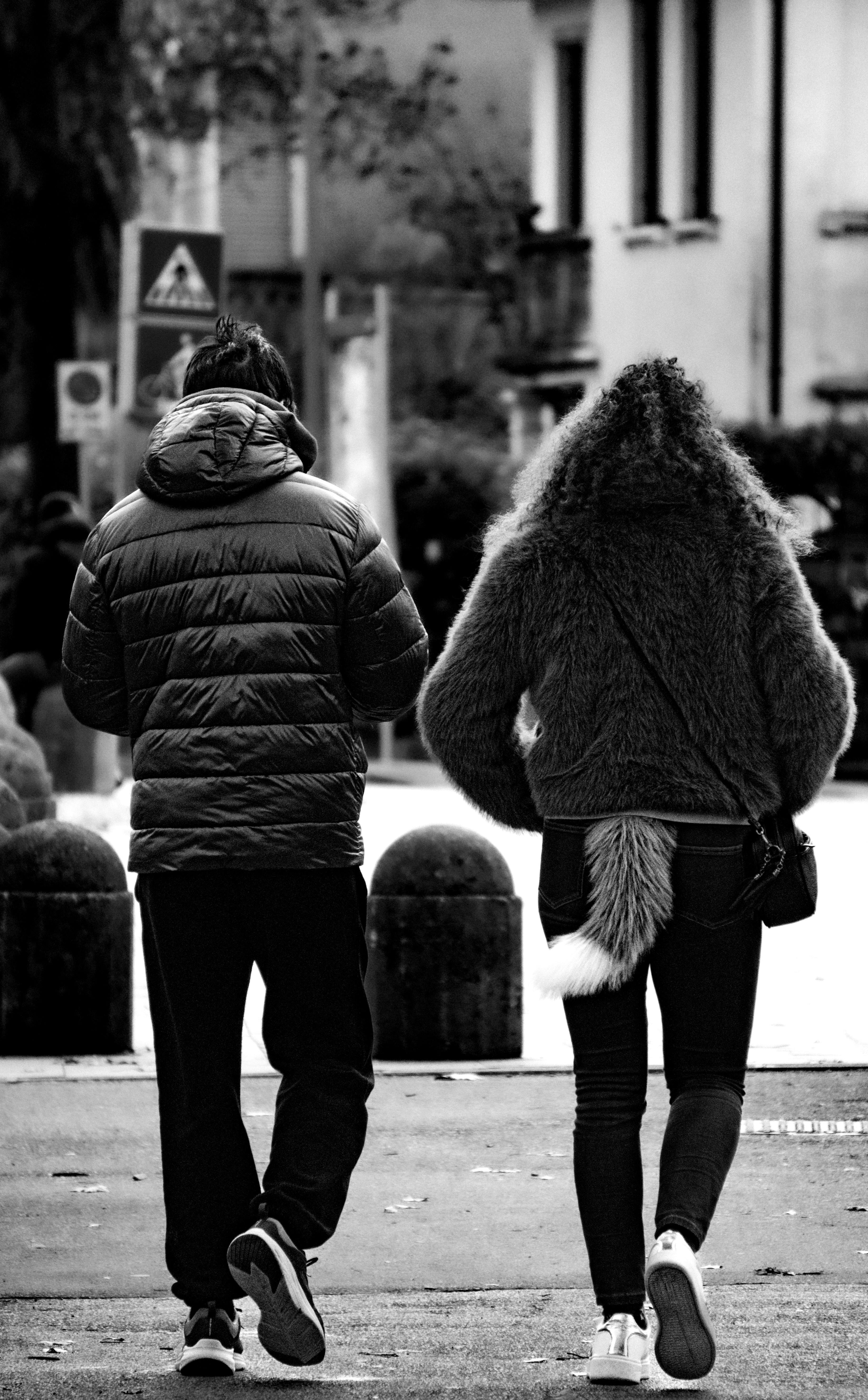 ฟรี ภาพด้านหลังของบุคคลสองคนกำลังเดินอยู่ในเมืองปาโดวา ประเทศอิตาลี โดยคนหนึ่งสวมเสื้อคลุมขนสัตว์มีหาง คลังภาพถ่าย