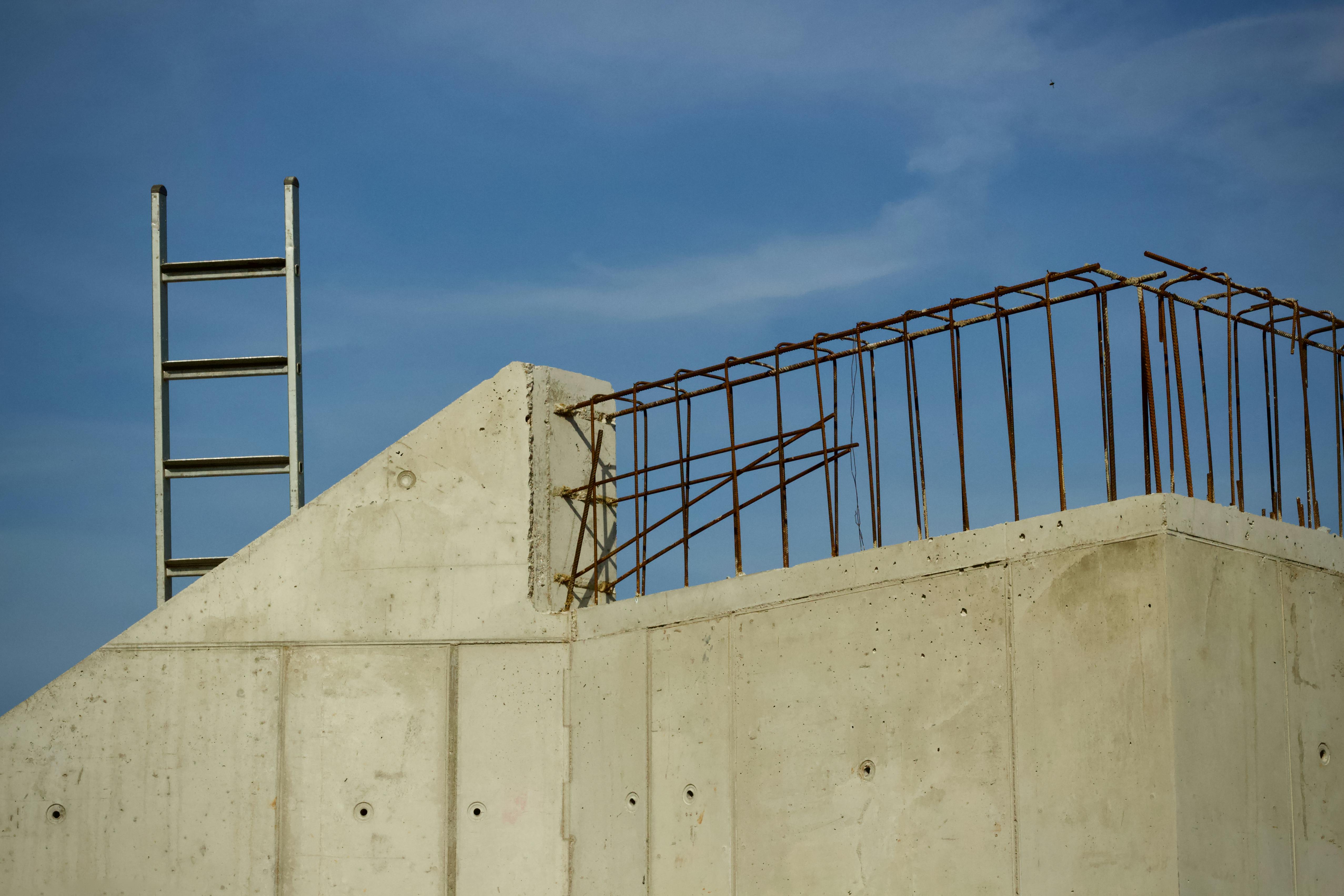 bezplatná Betonová stavba v procesu s žebříkem a výztuží proti jasné modré obloze. Základová fotografie