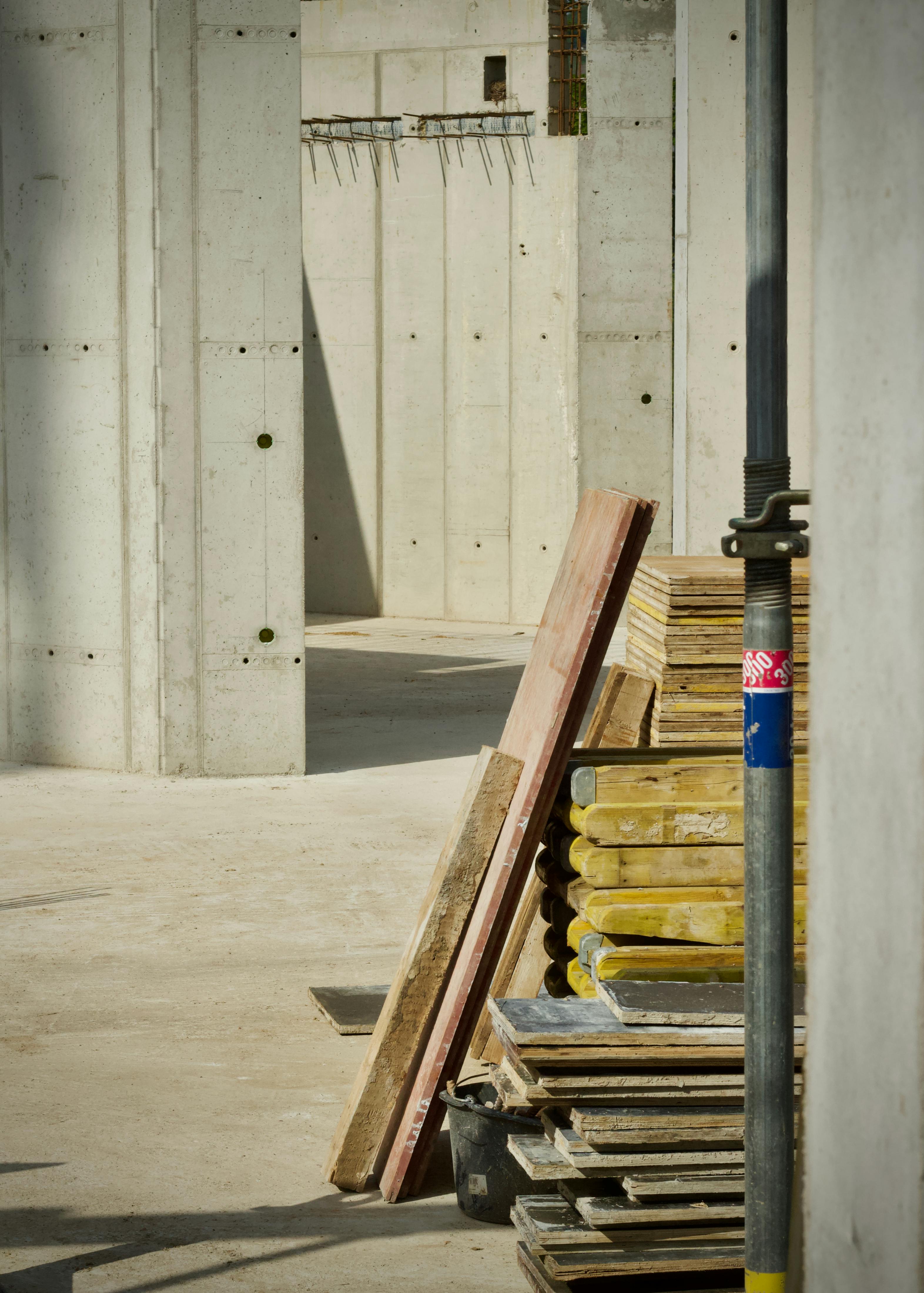 bezplatná Betonový průmyslový areál s naskládanými stavebními materiály a rozpracovanou konstrukcí. Základová fotografie