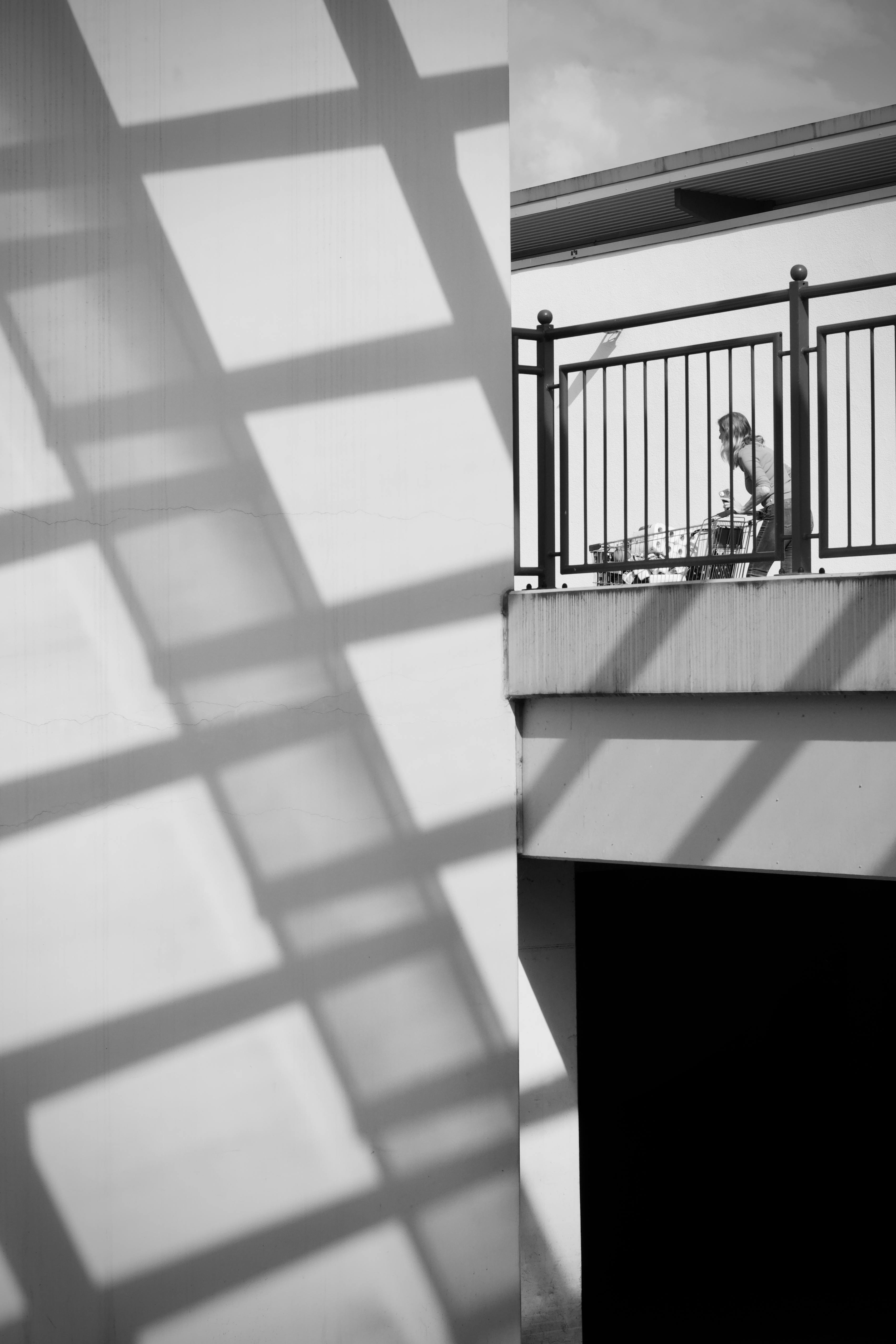 Gratis Suggestiva foto in bianco e nero di una persona su un balcone con ombre suggestive. Foto a disposizione