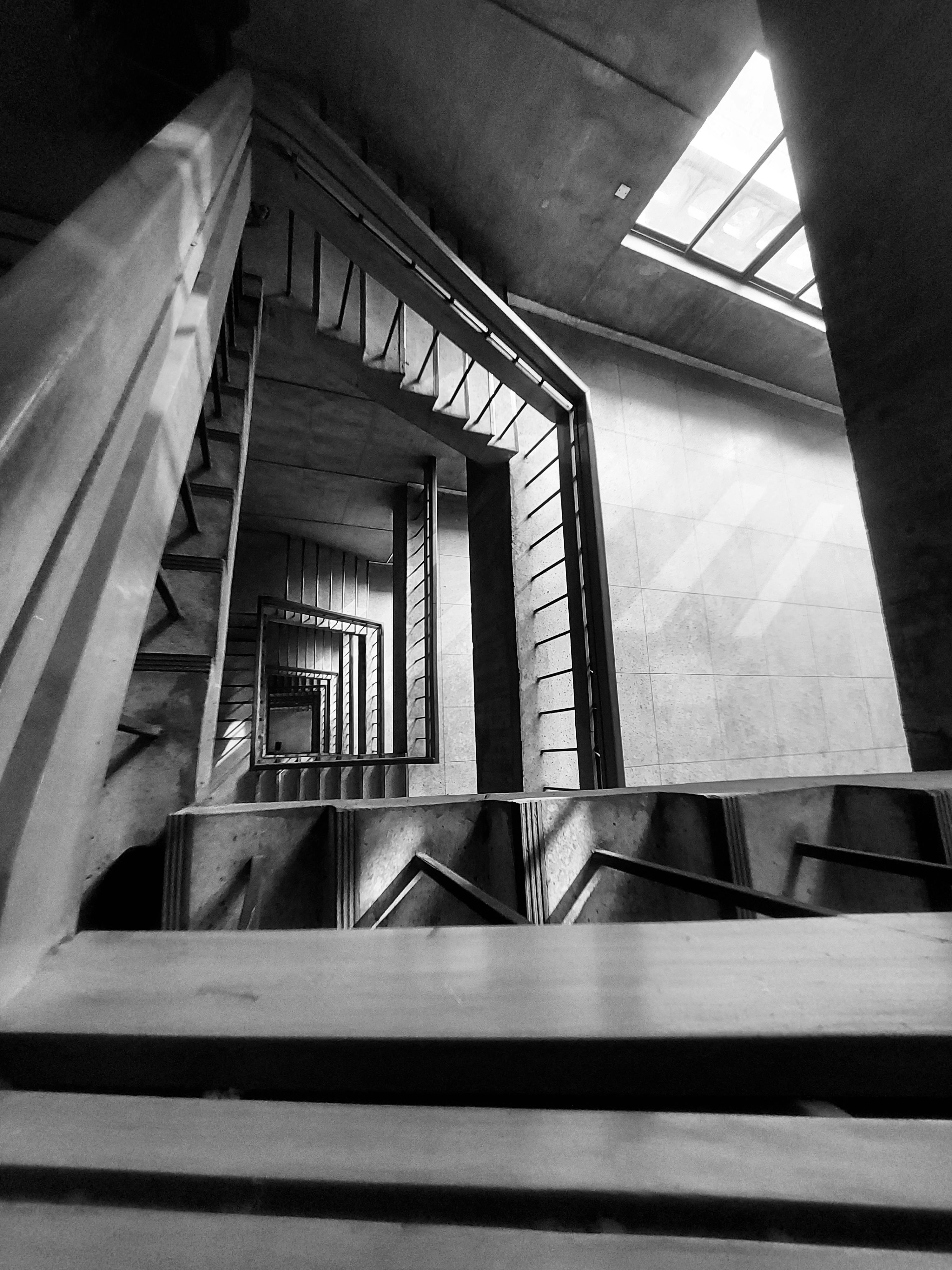 bezplatná Dramatická černobílá fotografie točitého schodiště s důrazem na geometrické linie a hloubku. Základová fotografie