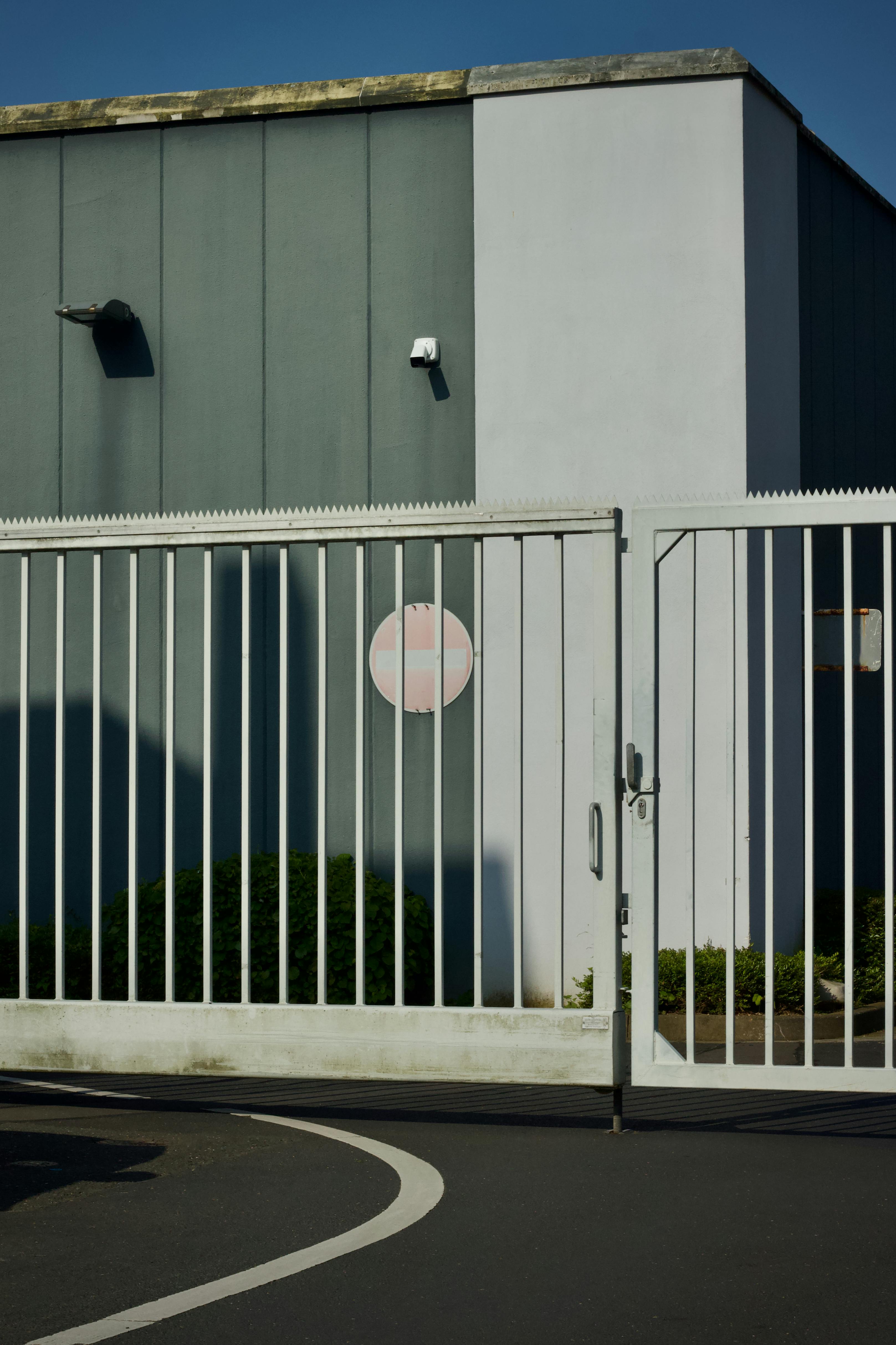 Gratis Fotografía de un edificio industrial seguro con una puerta de metal blanca, bajo un cielo azul claro. Foto de stock