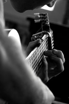 Black and white photo of a musician's hands skillfully playing an acoustic guitar.