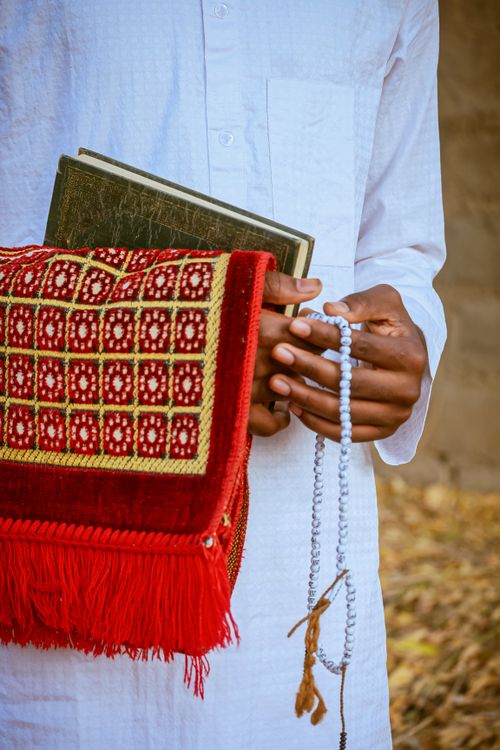 Man Holding Prayer Beads and Book with Red Bag · Free Stock Photo