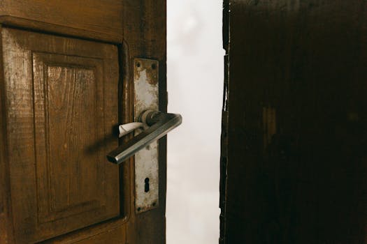 A rustic wooden door slightly ajar with a metal handle, creating a mysterious ambiance.