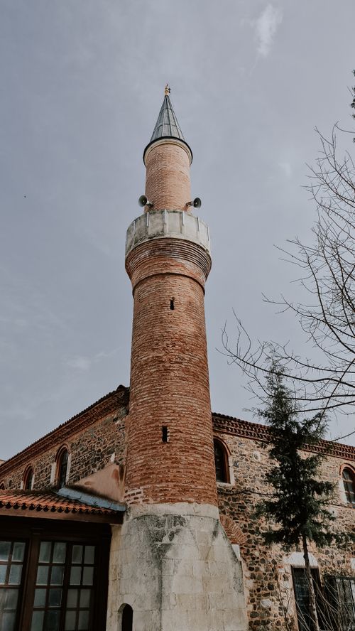 Free A tall brick minaret of an old mosque with a clear blue sky backdrop. Stock Photo