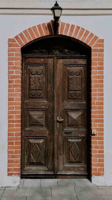 A rustic wooden door framed by a red brick arch, ideal for architectural themes.