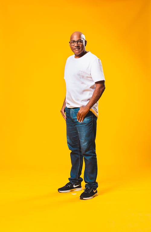 Man in White Crew Neck T-shirt and Blue Denim Jeans With A Yellow Background