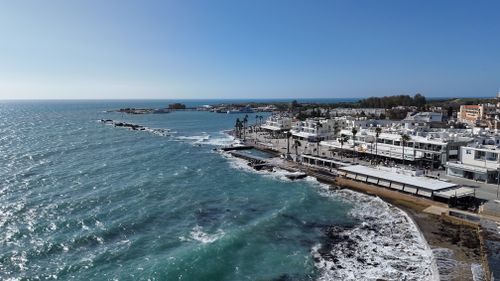 Free Explore Paphos' stunning coastline with vibrant waves and modern architecture from above. Stock Photo