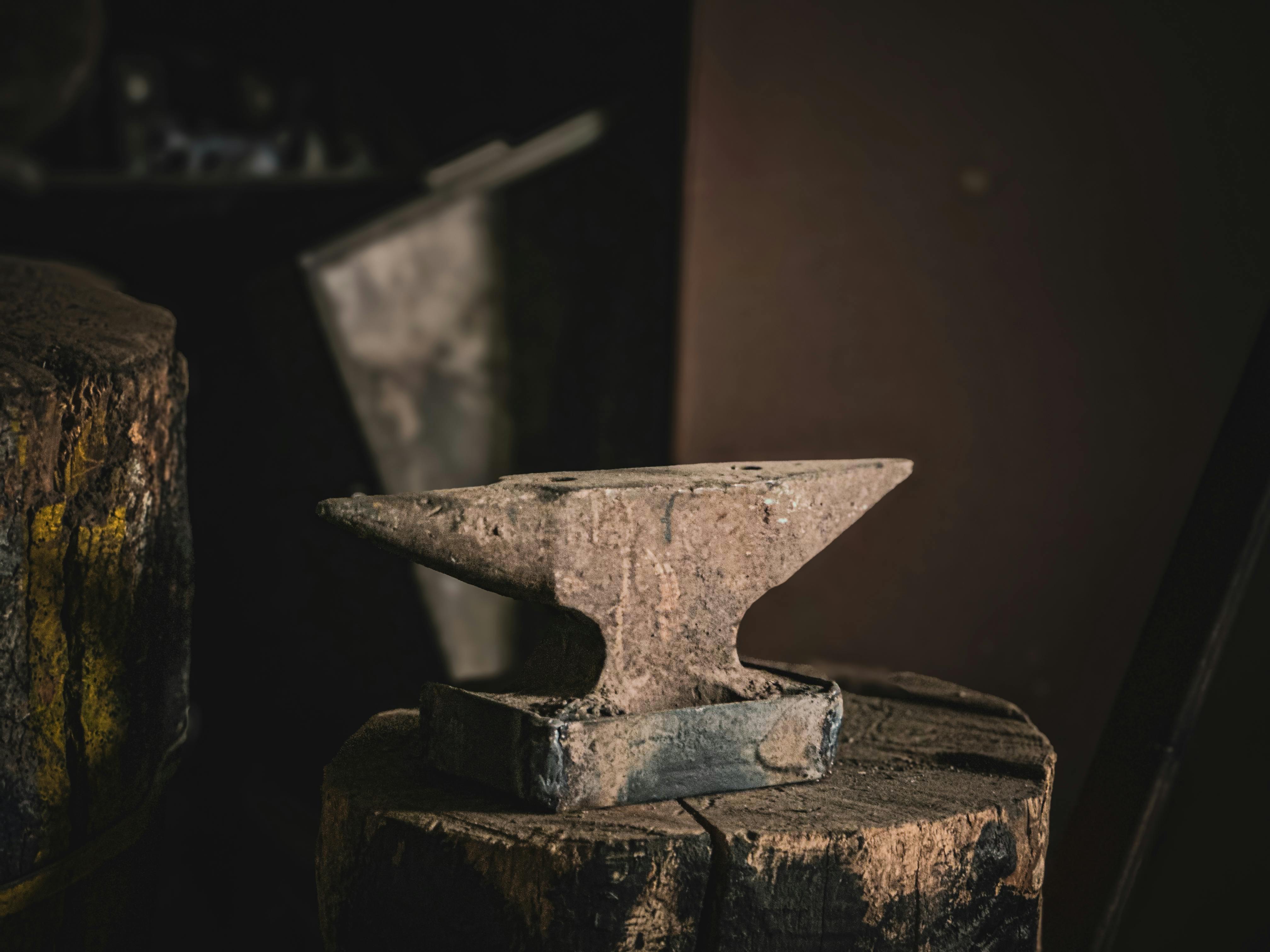 Gratis Un'incudine rustica è posta in cima a un ceppo di legno in un laboratorio scarsamente illuminato, a suggerire la tradizionale attività di forgiatura. Foto a disposizione