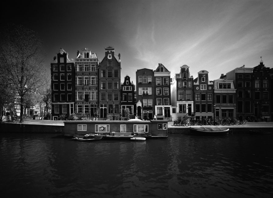 Monochrome view of historic canal houses and boats in Amsterdam.
